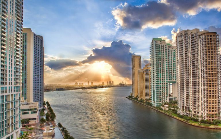 a river with tall buildings and sun rays